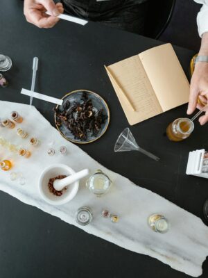 Overhead view of artisan crafting perfume using natural ingredients at a worktable.
