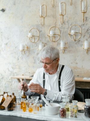 Senior perfumer blends fragrant ingredients in stylish indoor setting.